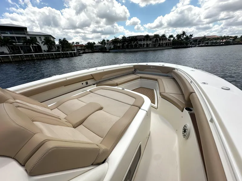Slide: The Image of 2020 Scout 380 LXF boat with luxurious seating, docked by waterfront homes under a cloudy sky. - 21