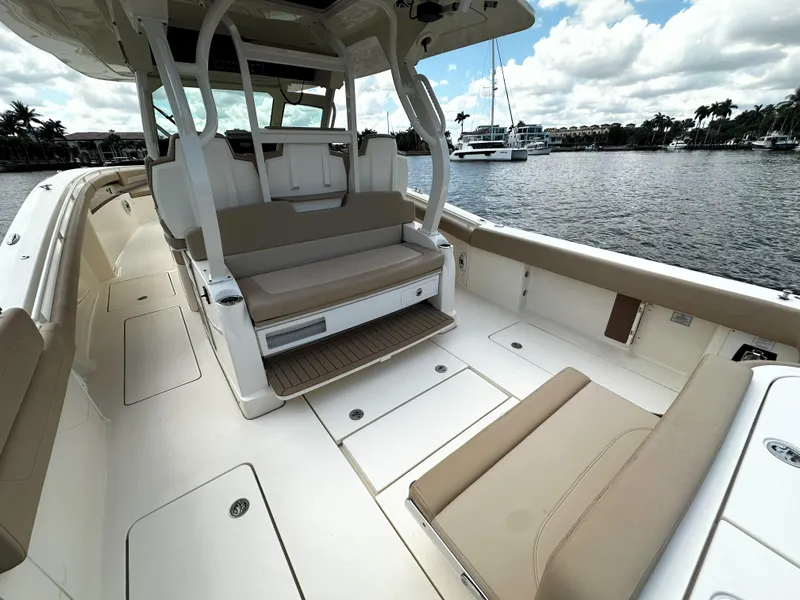 Slide: The Image of 2020 Scout 380 LXF boat interior with beige seating and open deck, docked by the water. - 6