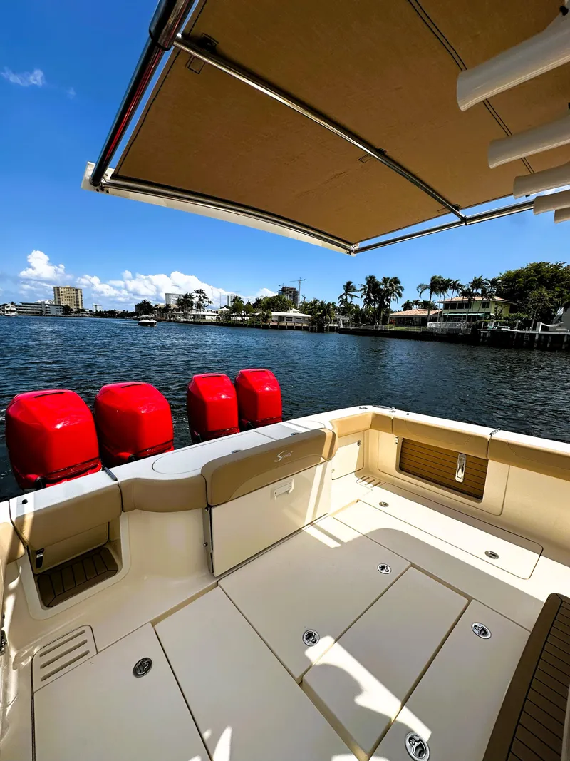Slide: The Image of 2020 Scout 380 LXF boat with red engines, docked by a scenic waterfront. - 7