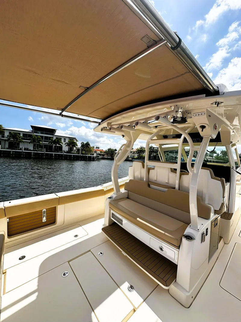 Slide: The Image of 2020 Scout 380 LXF boat with spacious seating and canopy, docked by waterfront homes. - 8