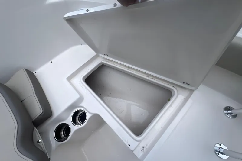 Slide: The Image of 2024 Key West 203 FS boat storage compartment with open lid and cup holders. - 20