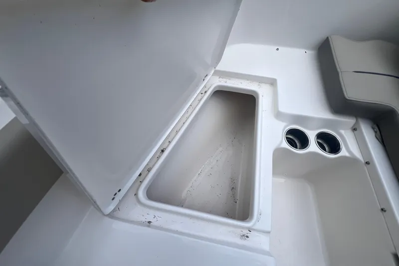 Slide: The Image of 2024 Key West 203 FS boat storage compartment with cup holders, open lid view. - 21