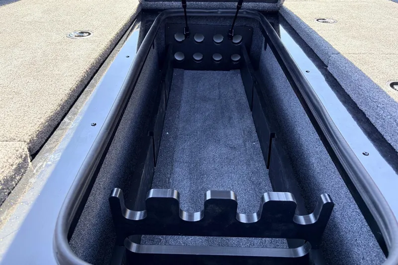 Slide: The Image of 2026 Ranger RT198P boat storage compartment with rod holders and carpeted interior. - 21