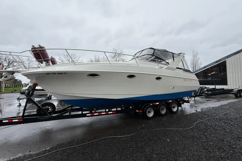 The Image of 1997 Larson Cabrio 310 Mid-Cabin boat on trailer, parked outdoors on a cloudy day. - 0