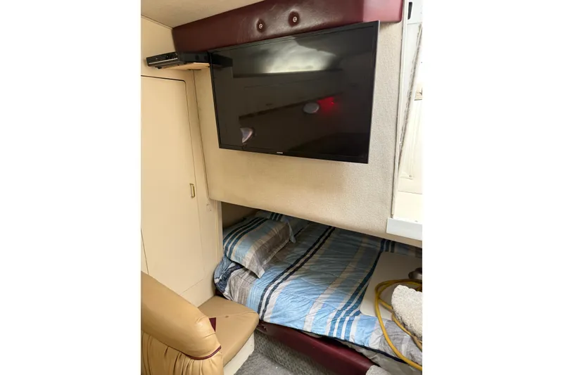 Slide: The Image of 1997 Larson Cabrio 310 Mid-Cabin interior with bed, TV, and storage. - 15