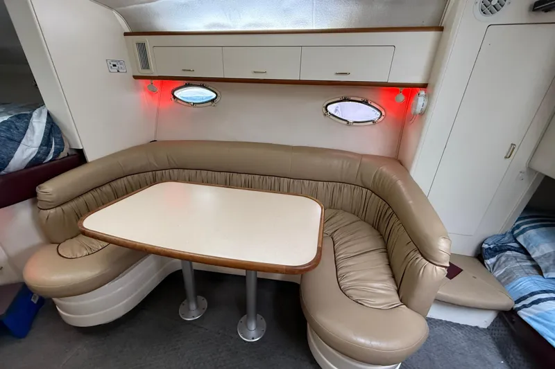 Slide: The Image of 1997 Larson Cabrio 310 Mid-Cabin interior with beige leather seating and dining table. - 18
