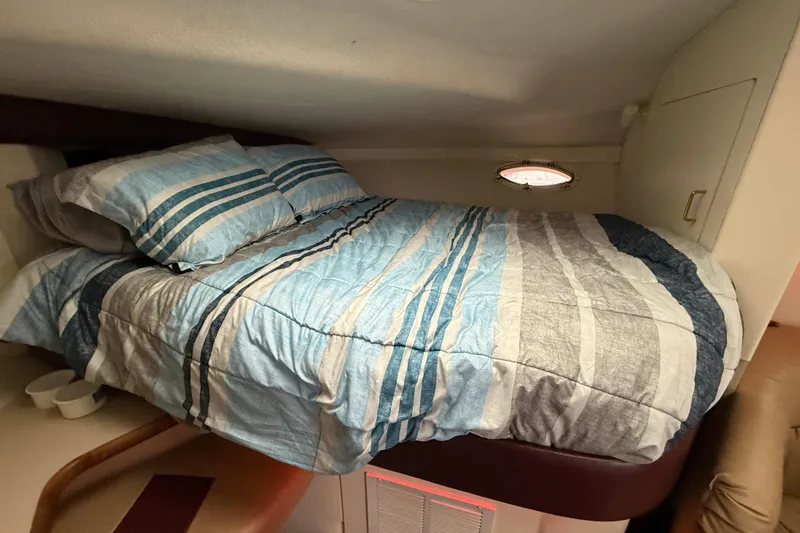 Slide: The Image of Cozy cabin bed in 1997 Larson Cabrio 310 Mid-Cabin boat with striped bedding. - 19
