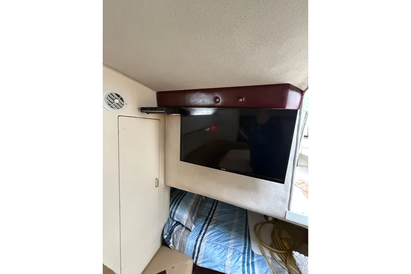 Slide: The Image of Interior of 1997 Larson Cabrio 310 Mid-Cabin with mounted TV and bedding. - 21