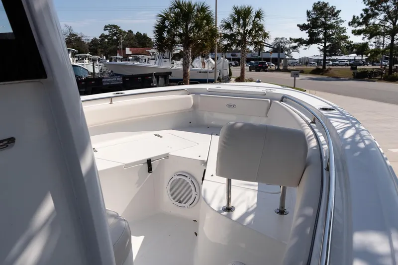 Slide: The Image of 2023 Sea Hunt Ultra 239 SE boat interior with seating and storage, parked outdoors. - 19