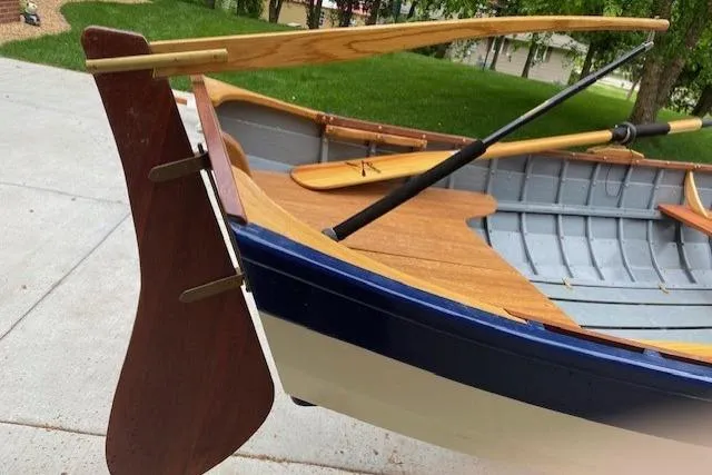 Slide: The Image of Handcrafted 2019 HOME BUILT Cat's Paw boat with wooden oars and rudder, docked on concrete. - 12
