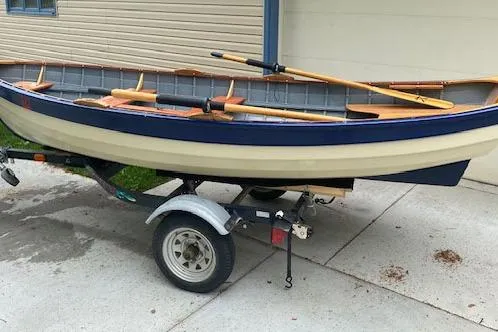 Slide: The Image of Home Built 2019 Cat's Paw boat on trailer, featuring wooden oars and classic design. - 16