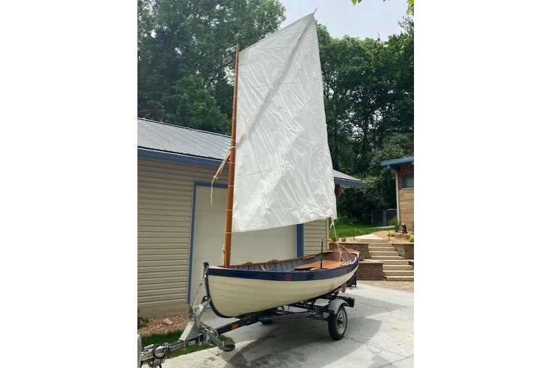 Slide: The Image of Home-built 2019 Cat's Paw sailboat on trailer, white sail raised, parked outdoors. - 17