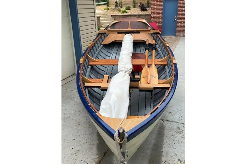 Slide: The Image of Handcrafted 2019 "Cat's Paw" boat with wooden oars and covered mast, docked in a garage. - 3