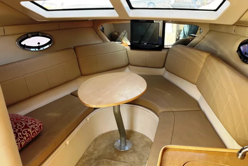 Slide: The Image of 2011 Regal 2565 Express Cruiser interior with beige seating and wooden table. - 10