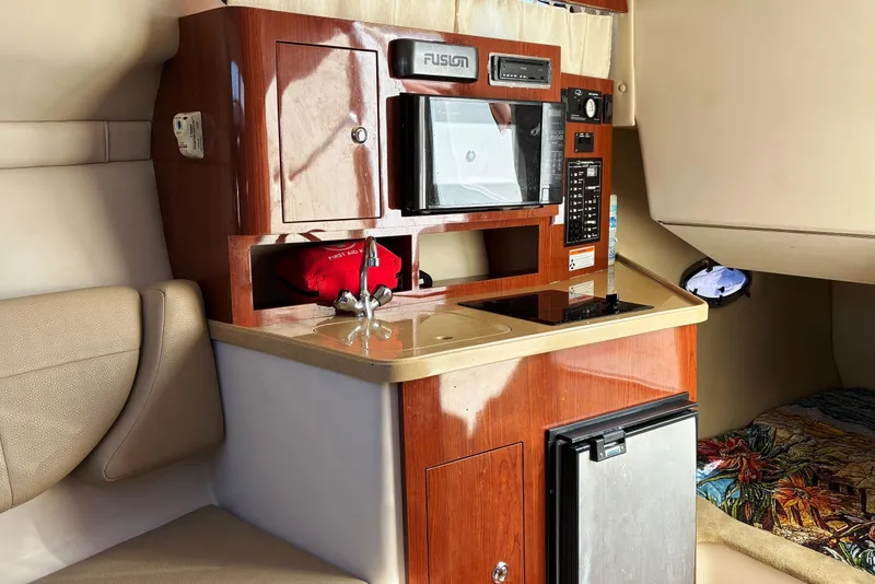 Slide: The Image of 2011 Regal 2565 Express Cruiser interior with kitchenette, microwave, and compact fridge. - 11