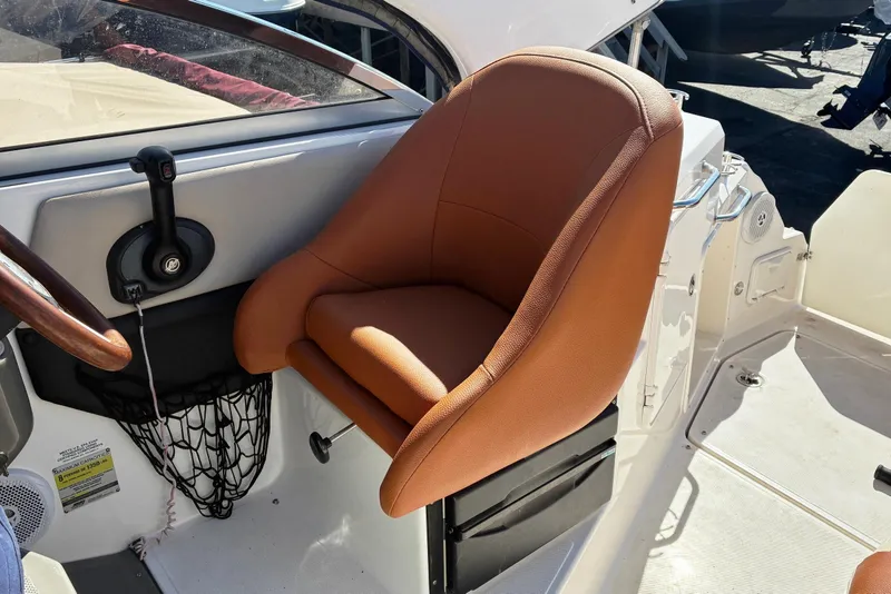 Slide: The Image of Captain's seat on 2011 Regal 2565 Express Cruiser boat, featuring brown upholstery and control panel. - 5