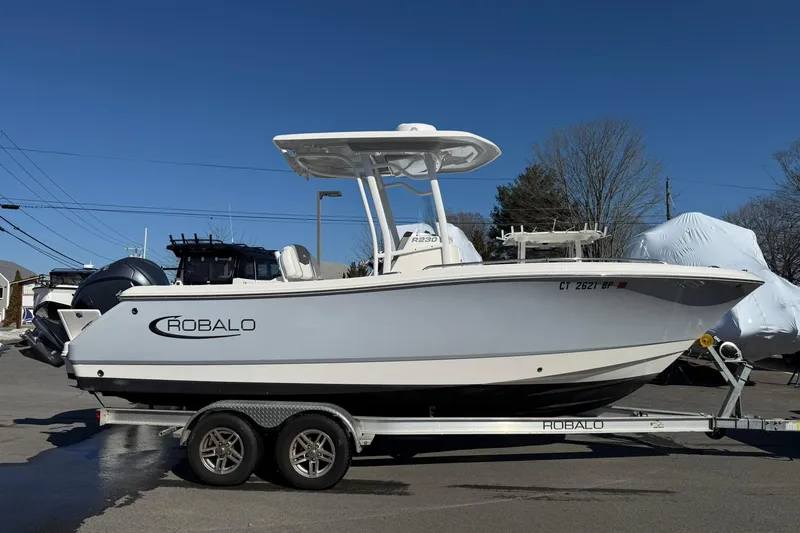 Slide: The Image of 2022 Robalo R230 Center Console boat on trailer, parked outdoors under clear blue sky. - 21