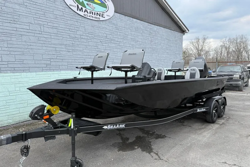 The Image of 2026 SeaArk Flex 21 Pro boat in black, parked on a trailer outside a marine shop. - 0