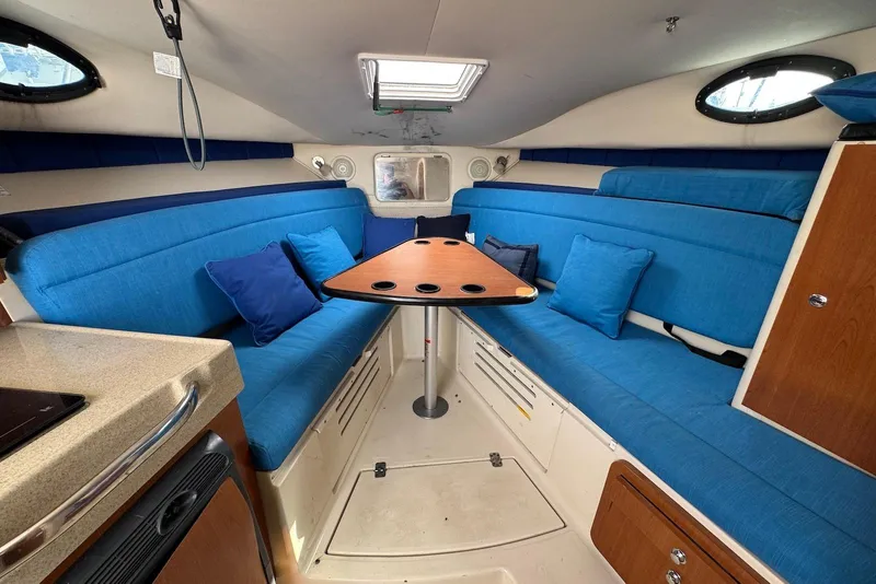 Slide: The Image of 2007 Wellcraft 290 Coastal cabin interior with blue seating and wooden table. - 16