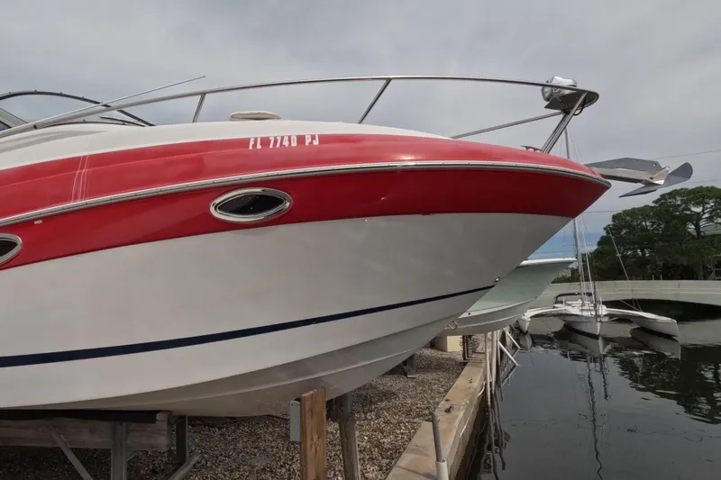 Slide: The Image of 2012 Four Winns V265 boat docked, featuring red and white hull design. - 2