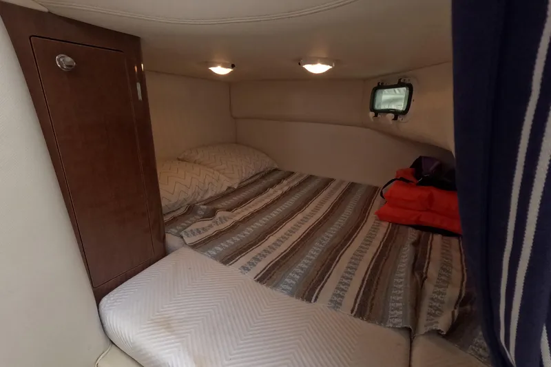 Slide: The Image of Cozy cabin interior of 2012 Four Winns V265 boat with striped bedding and wooden cabinet. - 44