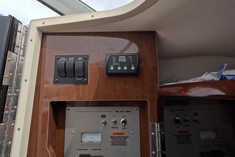 Slide: The Image of 2012 Four Winns V265 control panel with switches and gauges on wooden interior. - 47