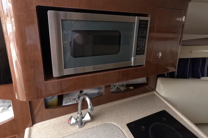 Slide: The Image of 2012 Four Winns V265 boat interior with microwave, sink, and countertop. - 48