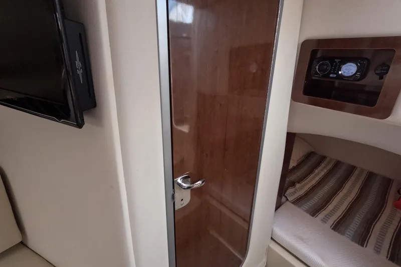 Slide: The Image of Interior of 2012 Four Winns V265 boat with wooden door, bed, and control panel. - 57