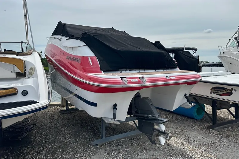 Slide: The Image of 2012 Four Winns V265 boat with red and white hull, covered and docked. - 81