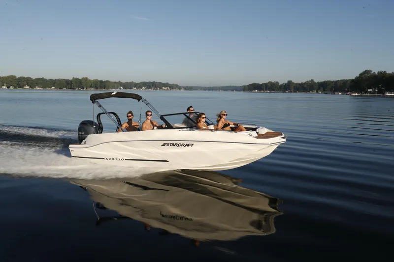 Slide: The Image of 2026 Starcraft SVX 210 DC OB boat cruising on a serene lake with passengers. - 23