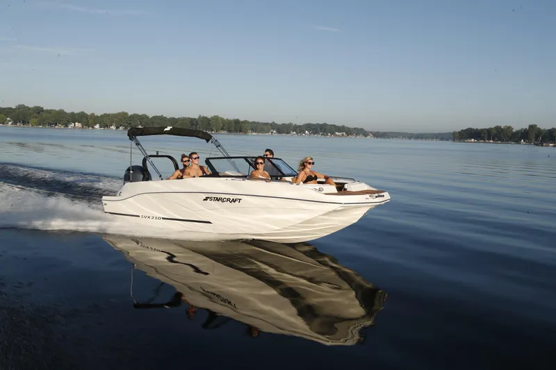 Slide: The Image of 2026 Starcraft SVX 210 DC OB boat cruising on a serene lake with passengers. - 24