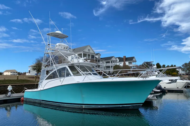 The Image of 2006 Luhrs 41 Open yacht docked, turquoise hull, clear sky, waterfront homes in background. - 0