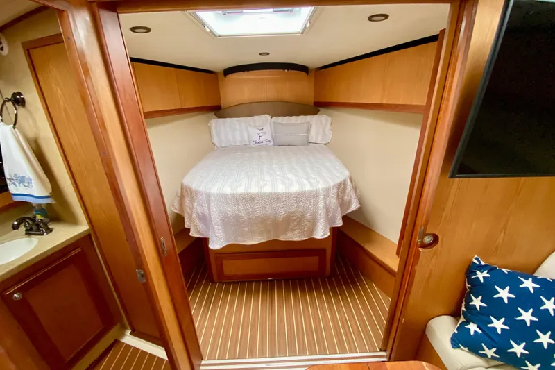 Slide: The Image of 2006 Luhrs 41 Open cabin interior with bed, wood paneling, and nautical decor. - 24