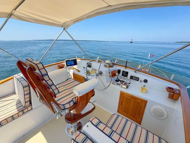 Slide: The Image of Helm of 1984 Wilbur 38 boat with striped seating, overlooking calm blue waters. - 10