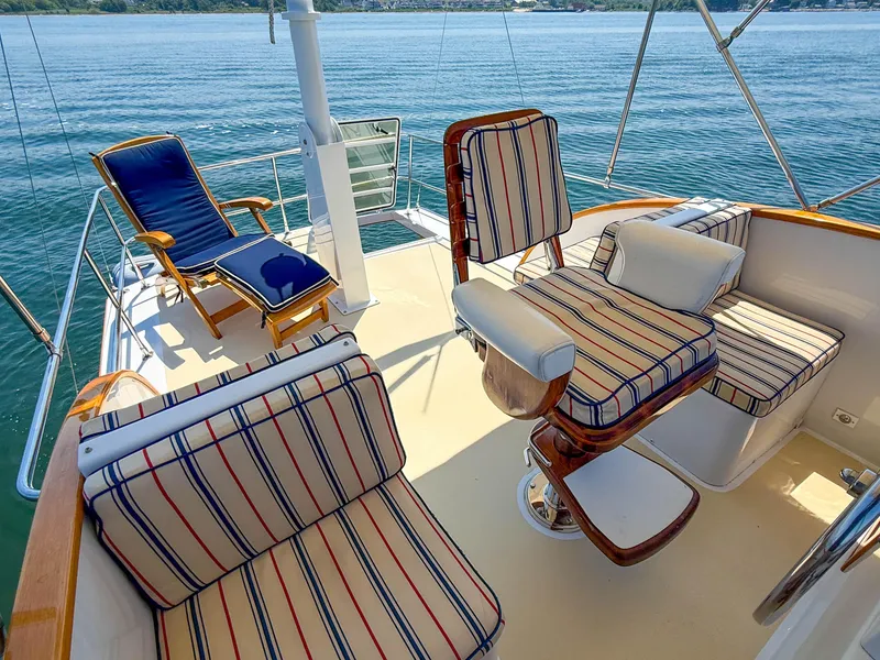 Slide: The Image of Luxury seating on 1984 Wilbur 38 yacht deck with striped cushions, overlooking serene water. - 11