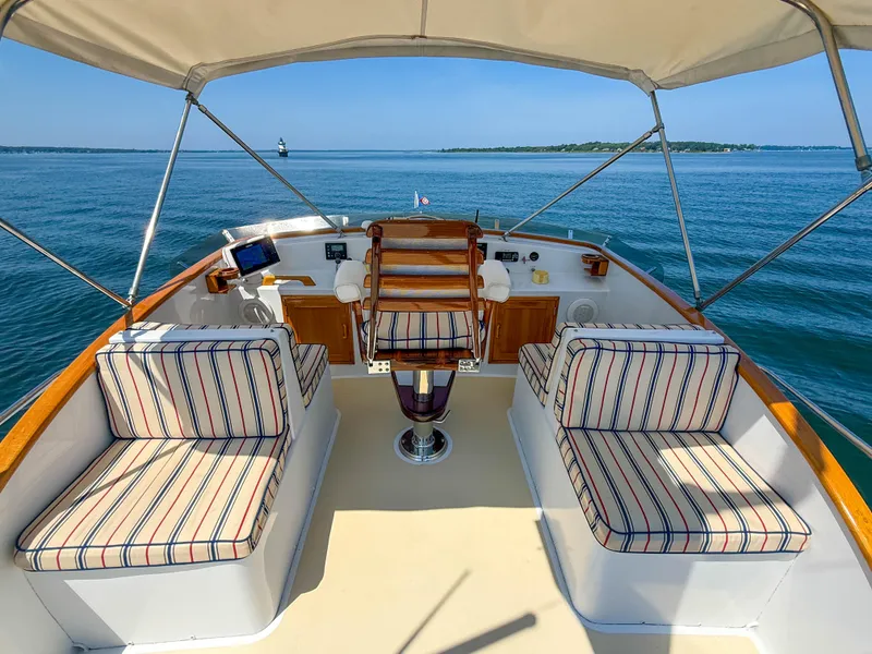 Slide: The Image of 1984 Wilbur 38 boat interior with striped seating, overlooking calm blue waters. - 13