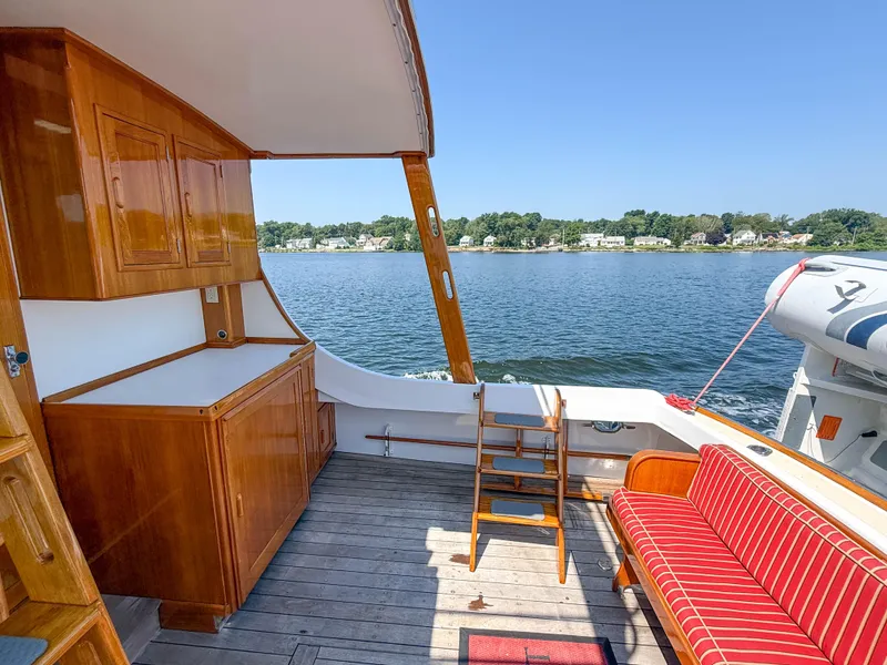 Slide: The Image of 1984 Wilbur 38 boat interior with wooden cabinetry, striped seating, and scenic water view. - 14