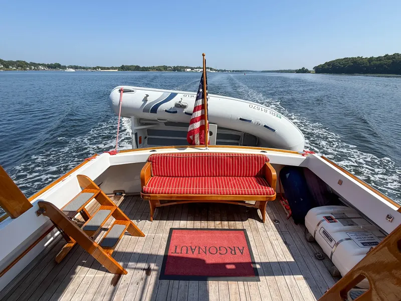 Slide: The Image of Vintage 1984 Wilbur 38 boat deck with red seating, American flag, and inflatable dinghy. - 16