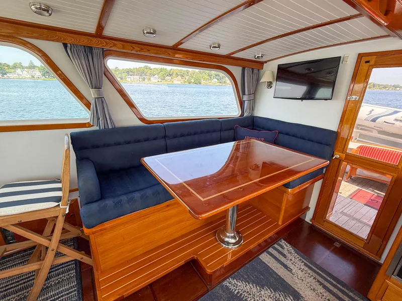 Slide: The Image of Interior of 1984 Wilbur 38 boat with wooden table, blue seating, and waterfront view. - 20