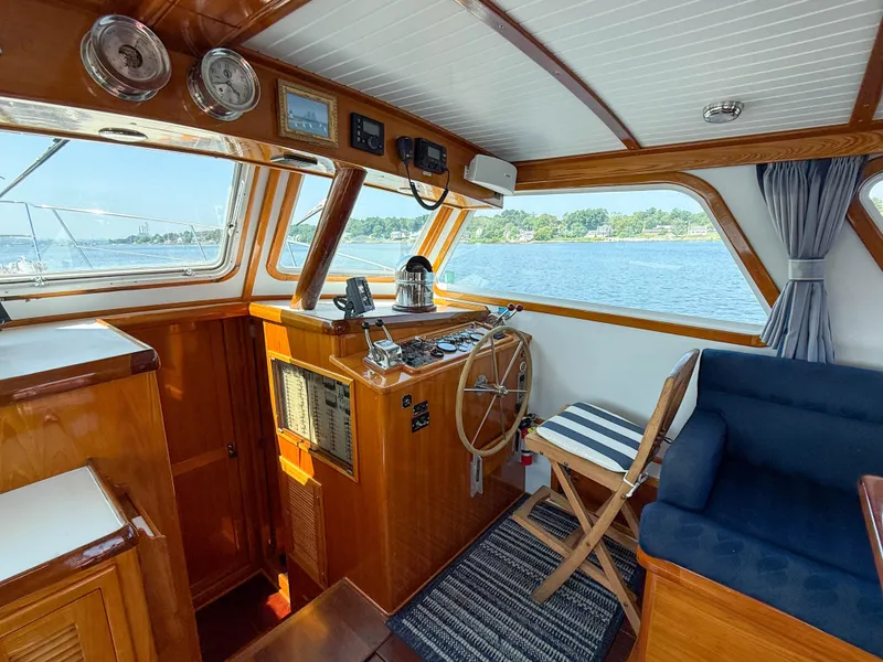 Slide: The Image of Interior of 1984 Wilbur 38 boat with wooden helm, striped chair, and scenic water view. - 22