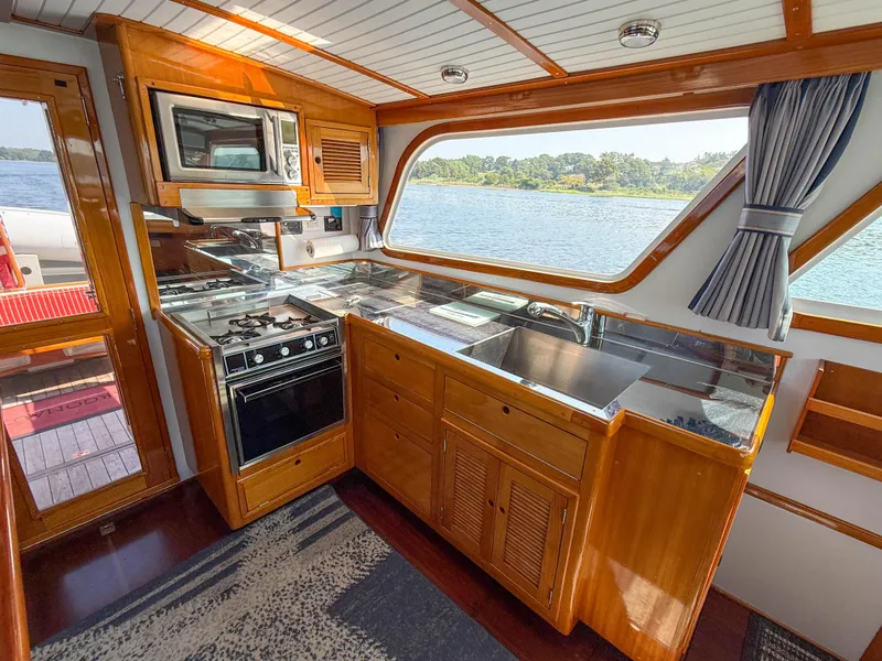 Slide: The Image of Kitchen area of a 1984 Wilbur 38 boat with wooden cabinetry and scenic water view. - 29