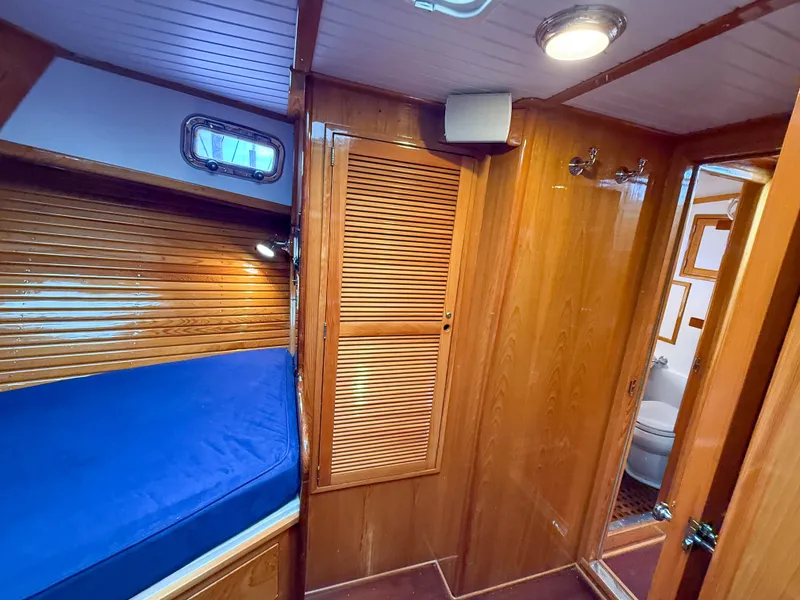 Slide: The Image of Wood-paneled cabin interior of 1984 Wilbur 38 boat with blue bedding and bathroom view. - 36
