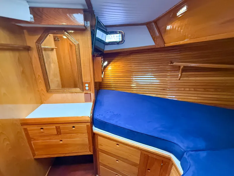 Slide: The Image of Cozy cabin interior of 1984 Wilbur 38 with wooden finish and blue bedding. - 37