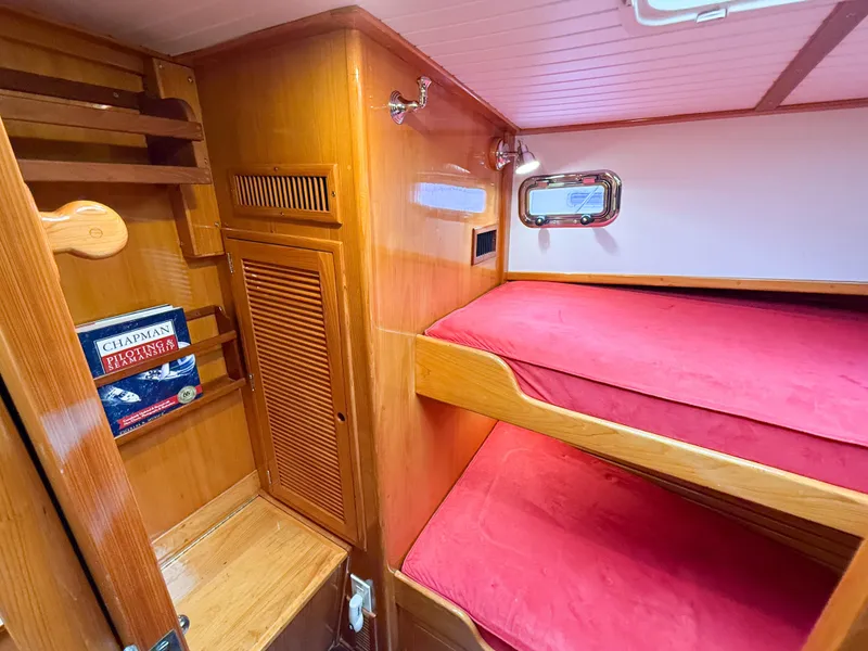 Slide: The Image of Cozy cabin interior of 1984 Wilbur 38 with red bunk beds and wooden shelving. - 40