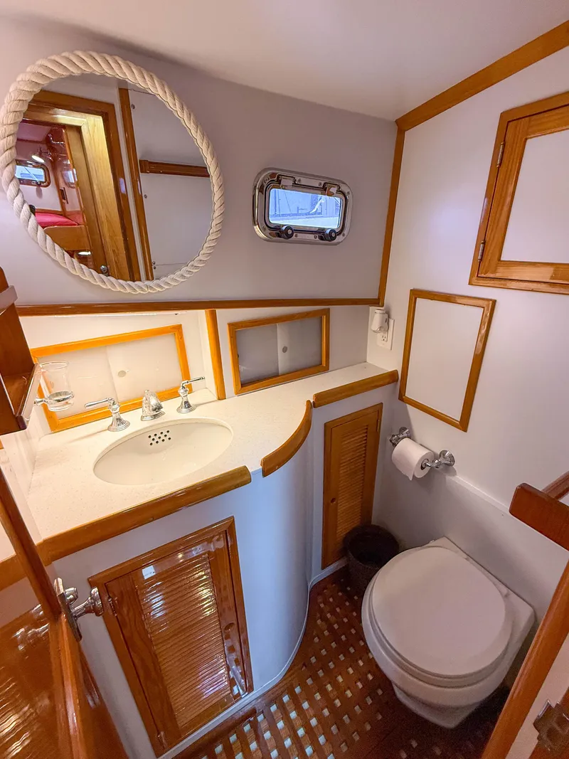 Slide: The Image of Compact 1984 Wilbur 38 boat bathroom with wooden accents, round mirror, and porthole window. - 42