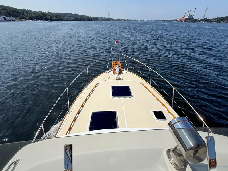 Slide: The Image of 1984 Wilbur 38 boat cruising on a calm river with scenic shoreline views. - 45