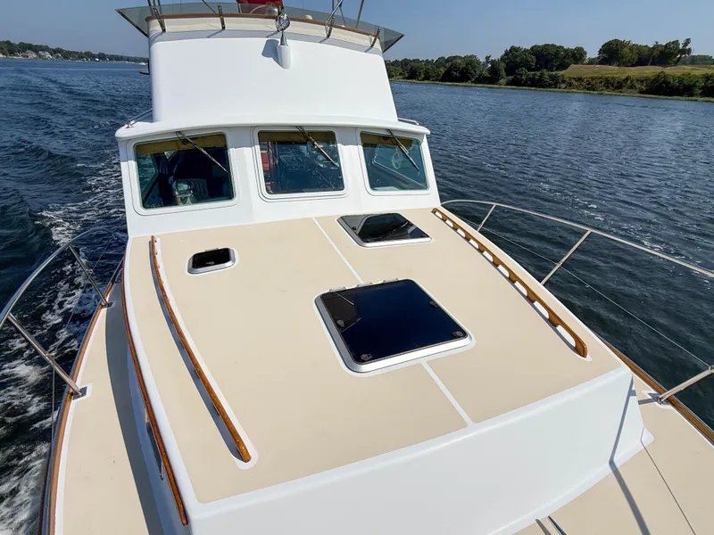 Slide: The Image of 1984 Wilbur 38 boat cruising on a calm river under clear skies. - 46