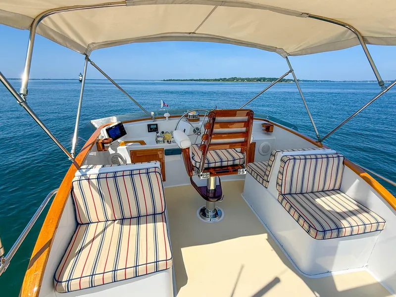 Slide: The Image of Cockpit of 1984 Wilbur 38 boat with striped seating, overlooking calm blue waters. - 7