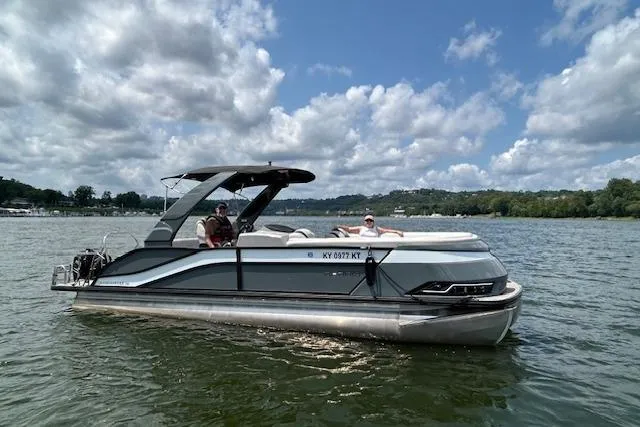 The Image of 2023 Harris Grand Mariner 250 SLDH pontoon boat on a scenic lake under a cloudy sky. - 1
