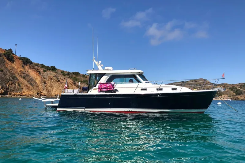 The Image of 2016 Sabre 38 Salon Express yacht anchored in clear blue water near rocky coastline. - 0